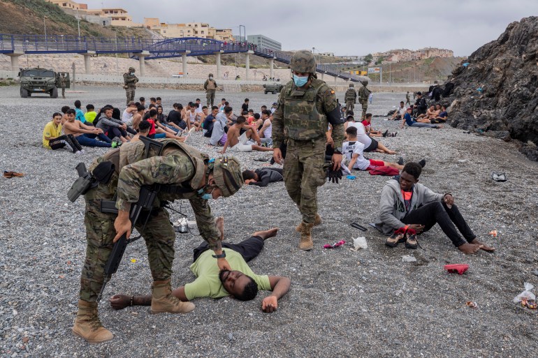 مهاجر يساعده جنود من الجيش الإسباني بالقرب من الحدود المغربية وإسبانيا، في جيب سبتة الإسباني، يوم الثلاثاء، 18 مايو 2021. (AP Photo/Bernat Armangue)