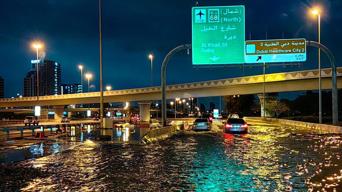 سائقو السيارات يقودون سياراتهم على طول شارع غمرته المياه بعد هطول أمطار غزيرة في دبي الأسبوع الماضي.  الصورة: وكالة فرانس برس