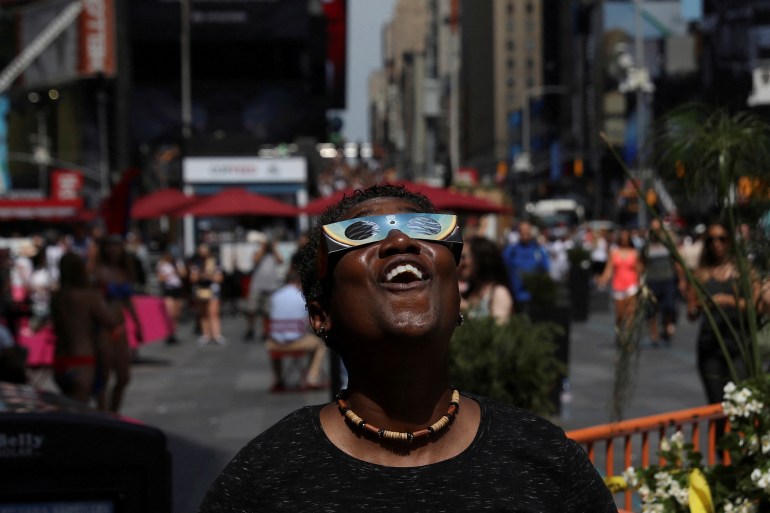 امرأة تشاهد كسوف الشمس في تايمز سكوير في مدينة نيويورك