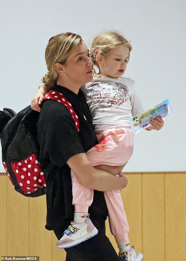 لقد احتضنت بلطف ابنتها هاربر، البالغة من العمر ثلاثة أعوام، بين ذراعيها أثناء سيرهما عبر المطار استعدادًا لسفرهما