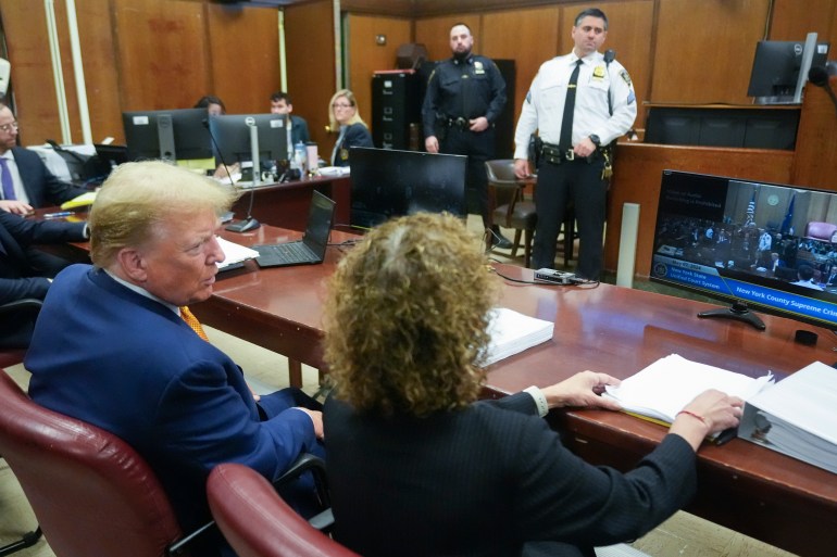 يظهر دونالد ترامب من الخلف وهو يجلس مع المحامية سوزان نيتشلز في محاكمته الجنائية في نيويورك.